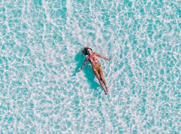 girl in pink bikini floating in ocean viewed from above
